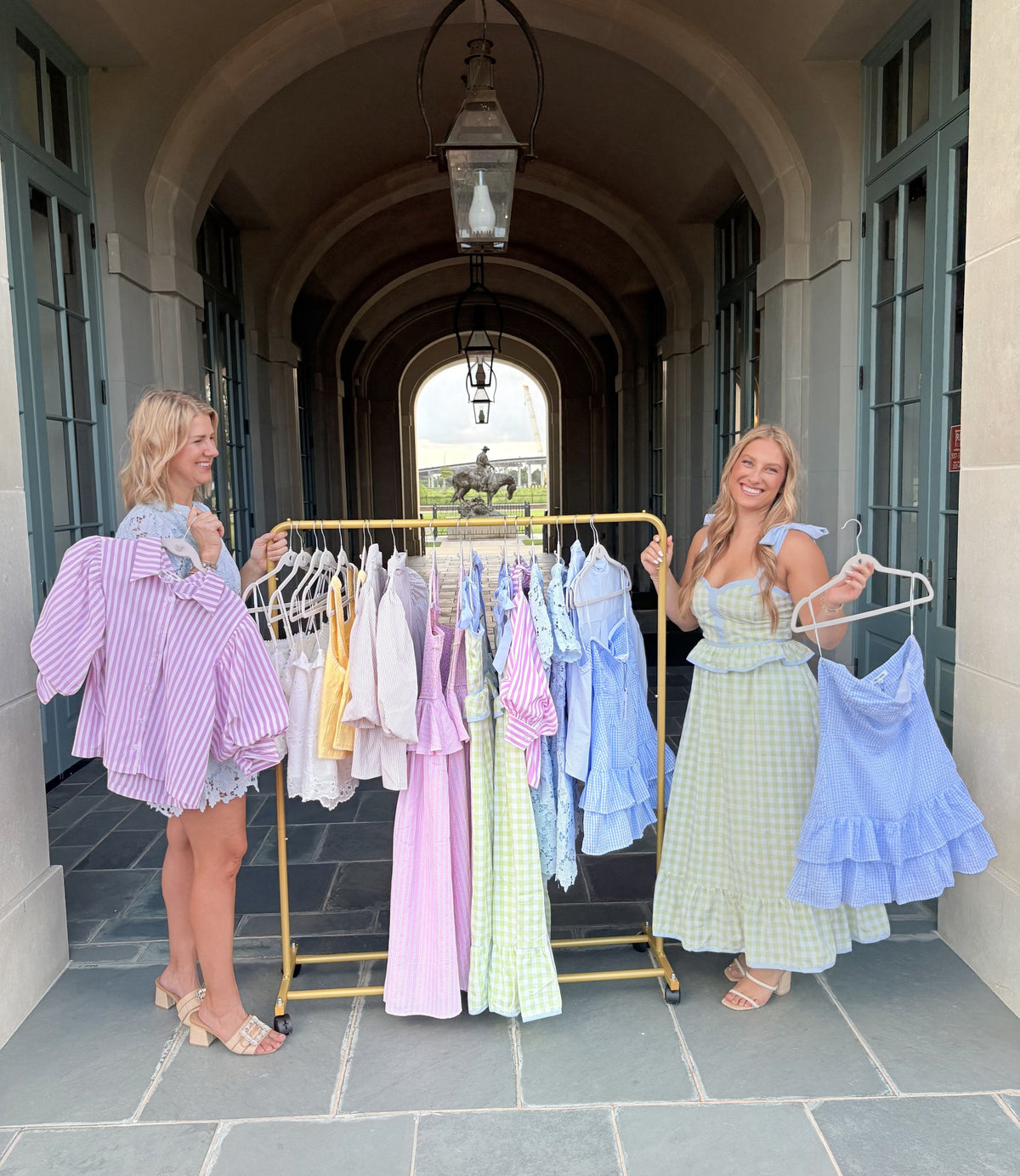 Southern Standard Boutique founders with a rack of dresses under an archway